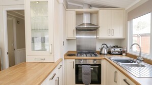 A compact kitchen with a stove, oven, and sink. - Lake View Lodge (Windermere)