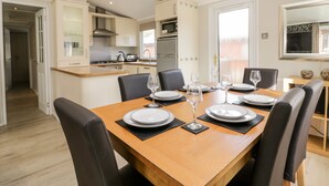 A dining area with a wooden table set for four, surrounded by chairs. - Lake View Lodge (Windermere)