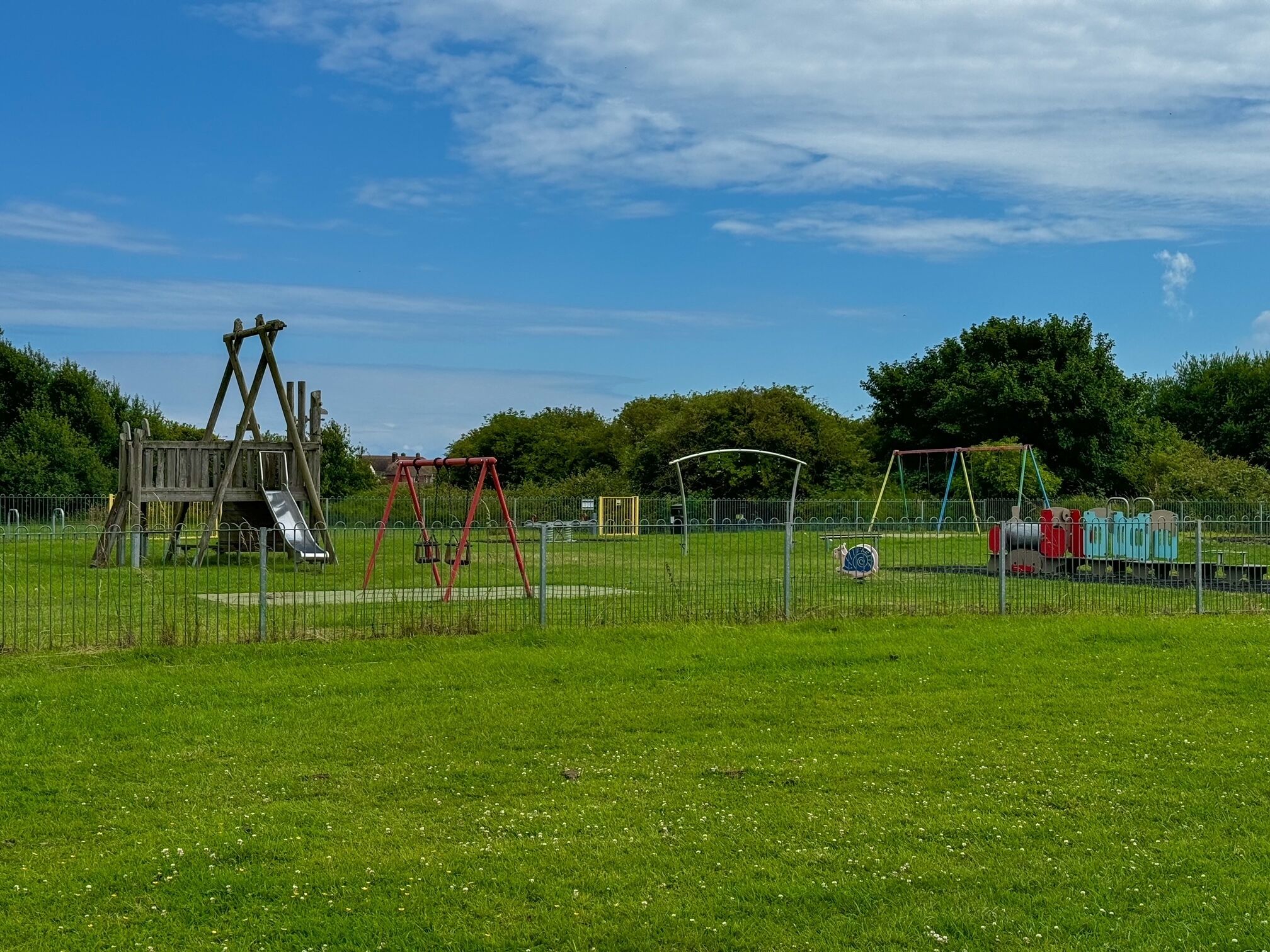 Un parque infantil con columpios, tobogán y estructura para escalar.