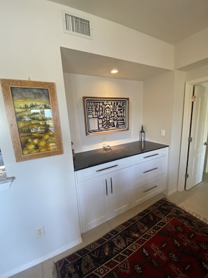 A kitchen with white cabinets, a black countertop, and a decorative painting above the sink.