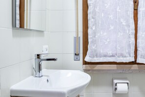 A bathroom with a white sink, chrome faucet, and a toilet paper holder. - Graziella House (Brenzone sul Garda)