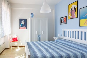 A bedroom with a bed, a chair, a wardrobe, and wall art.