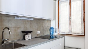 A kitchen with a double sink, a scale, and a window with sheer curtains. - Graziella House (Brenzone sul Garda)