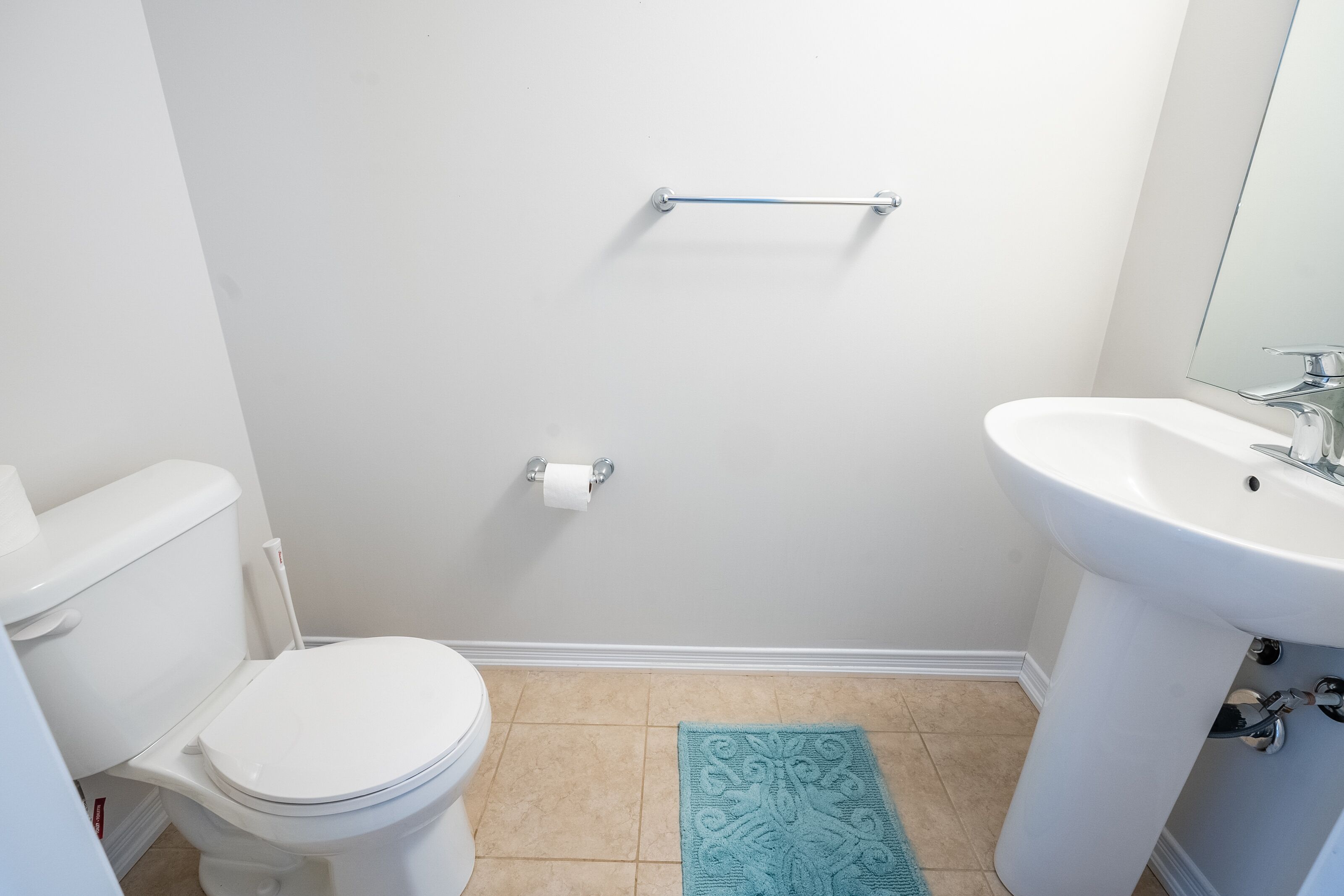 Un baño con inodoro, lavamanos y un perchero para toallas.