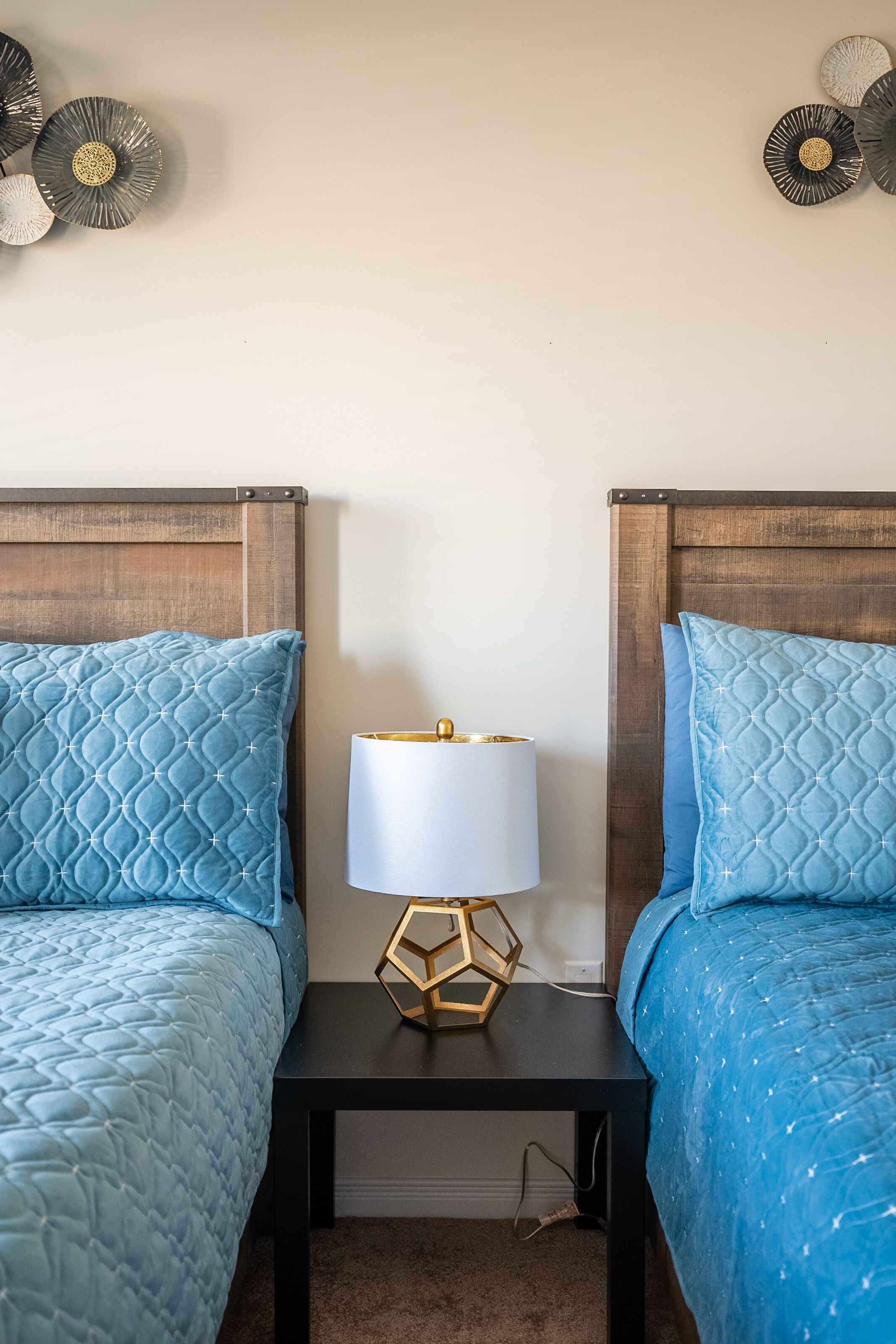 Una camera da letto con due letti, un comodino con lampada e decorazioni alle pareti.