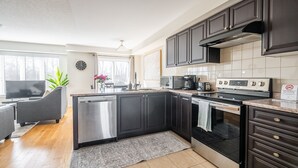 Une cuisine moderne avec des meubles de couleur sombre, des appareils électroménagers en acier inoxydable et un grand îlot central.