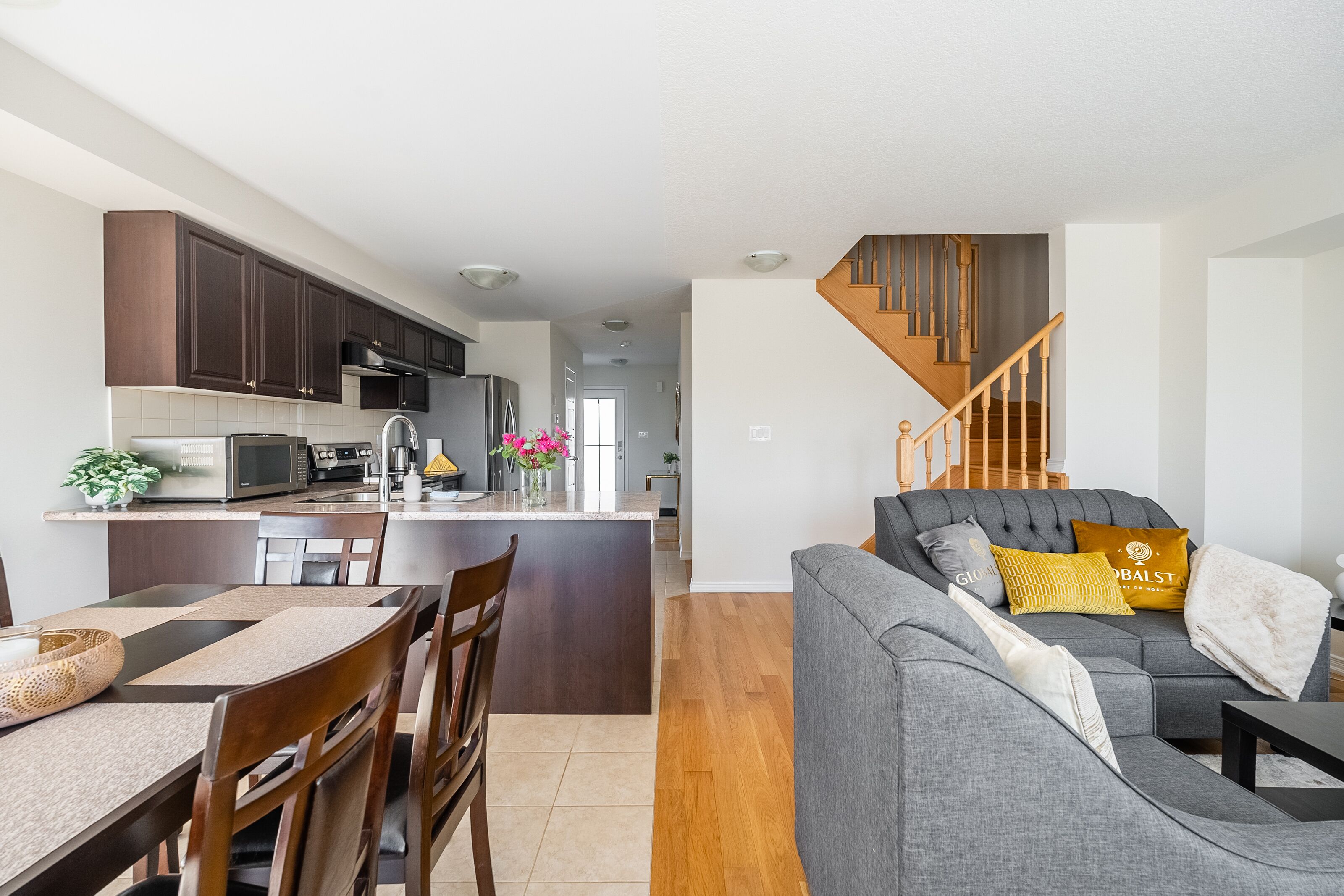 A modern kitchen with dark cabinets, a central island, and a dining area with a table and chairs.