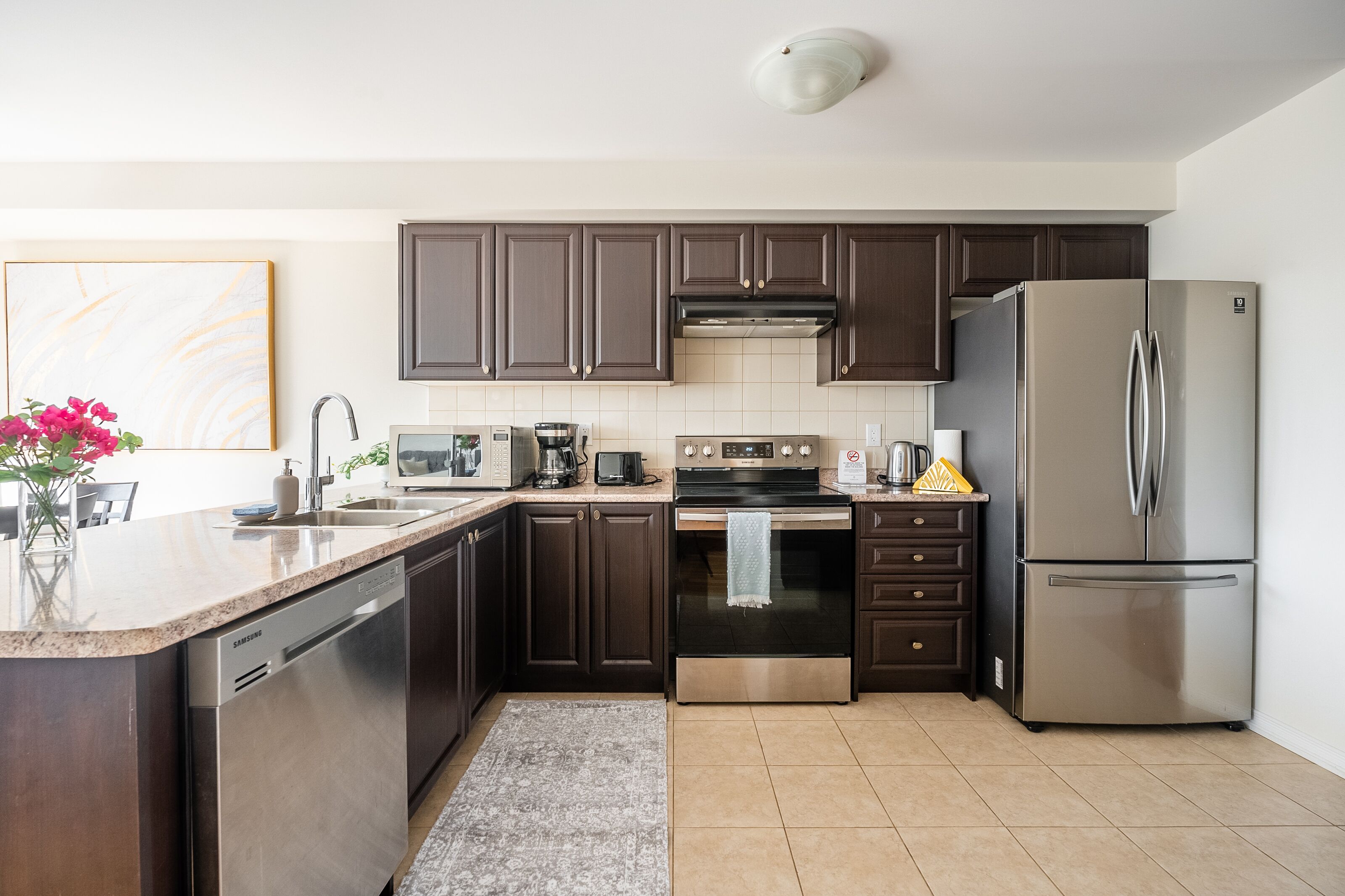 A modern kitchen with dark cabinets, stainless steel appliances, and a granite countertop.
