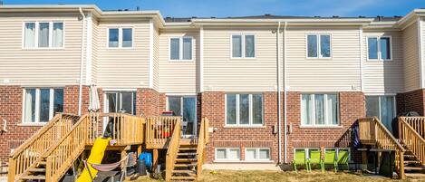 A row of townhouses with wooden decks and a yellow slide.
