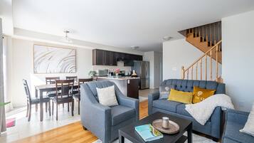 Una sala de estar moderna con un sofá gris, una mesa de centro y un comedor con sillas y una mesa de madera.