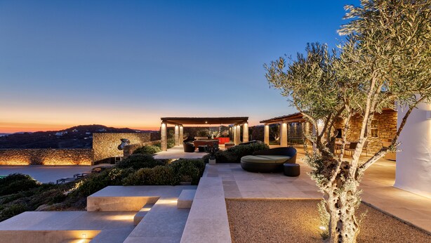 Un patio moderno al aire libre con pérgola, zona de estar y vistas al mar.