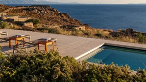 Zona de piscina con sillas de descanso y vista al mar.