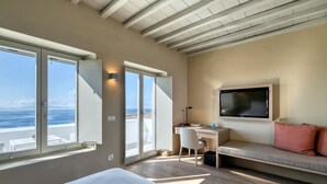 Un dormitorio moderno con una cama grande, un escritorio, un televisor y un sofá.