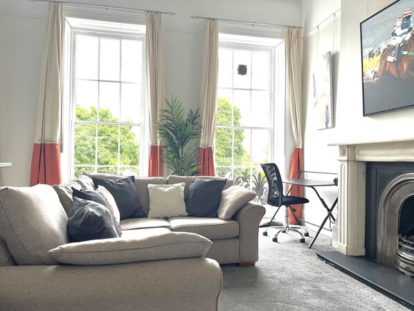 A living room with a sofa, a chair, a fireplace, and large windows with curtains. - Regency apartment in central Montpellier sleeps 4 - Pass the Keys (Cheltenham)
