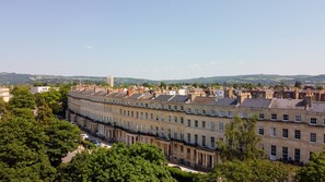 A row of uniform, historic buildings with a central courtyard and a view of the surrounding landscape.