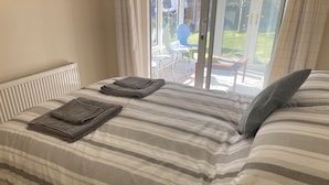 Un dormitorio con cama, dos toallas dobladas, un radiador y vistas al exterior.