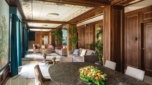 Un amplio salón con una gran mesa de mármol, sofás y plantas en macetas.