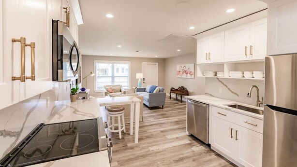 Una cocina moderna con armarios blancos, electrodomésticos de acero inoxidable y una isla central.