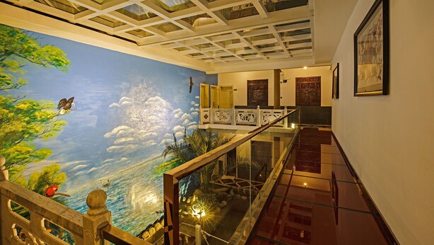 A spacious indoor area with a high ceiling, a mural of a landscape with clouds, and a staircase leading to an upper level. - China Old Story Inns Dali Elite Garden (Dali)