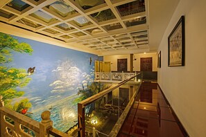 A spacious indoor area with a high ceiling, a mural of a landscape with clouds, and a staircase leading to an upper level. - China Old Story Inns Dali Elite Garden (Dali)