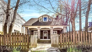 A house with a front porch, a wooden fence, and a stone staircase leading to the door. - 1929 Historic Craftsman Bungalow | King Bed (Atlanta)