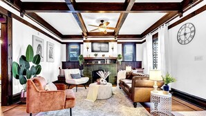 A living room with a fireplace, two sofas, a coffee table, and a side table with a lamp. - 1929 Historic Craftsman Bungalow | King Bed (Atlanta)