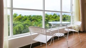 Une pièce dotée d’une grande fenêtre, de deux chaises en métal blanc et d’une table en verre.