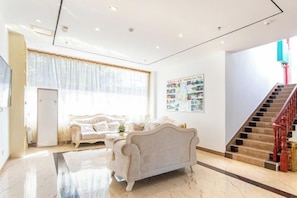 A spacious living area with a sofa, a coffee table, and a staircase. - Jinxiu Holiday Hotel (Yangshuo)