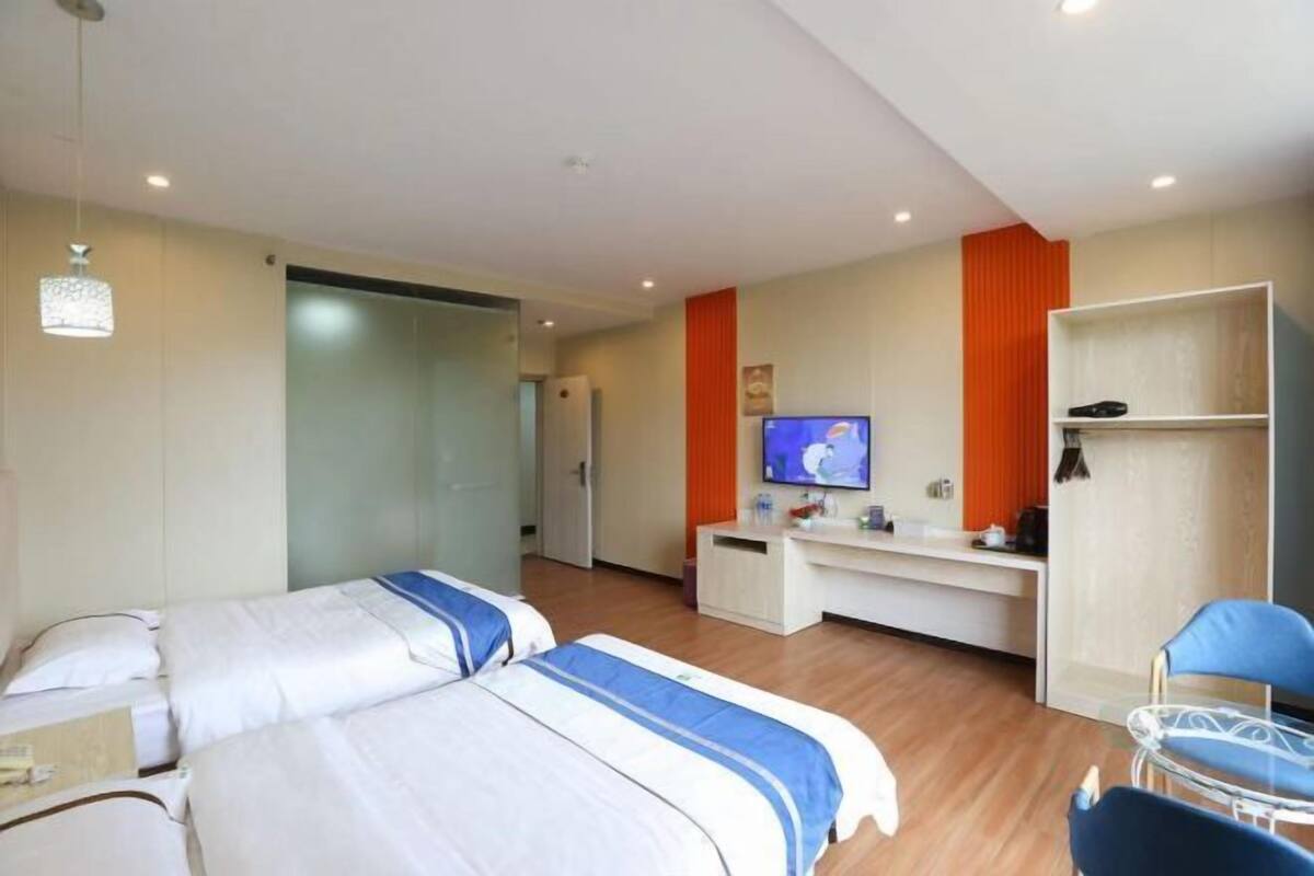 A hotel room with two beds, a desk, a television, a wardrobe, and a chair.