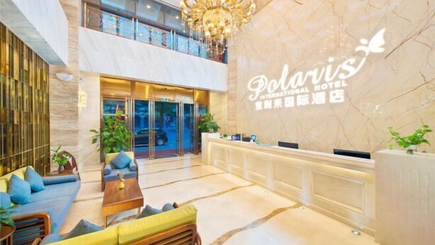 Un vestíbulo de hotel con mostrador de recepción, zona de estar y candelabro.
