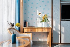 A modern room with a glass table, a blue vase, and a wooden desk with a plant. - Polaris International Hotel (Ledong)