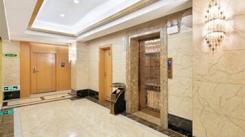 A hotel lobby with a marble floor, a reception desk, and an elevator.