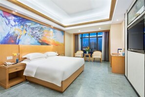 Habitación de hotel con una cama grande, un escritorio con silla, televisión y un cuadro en la pared.