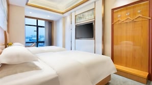 Habitación de hotel con una cama grande, televisión, armario y vistas a la ciudad.