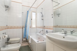 Ein Badezimmer mit Toilette, Bidet, Badewanne und zwei Waschbecken.