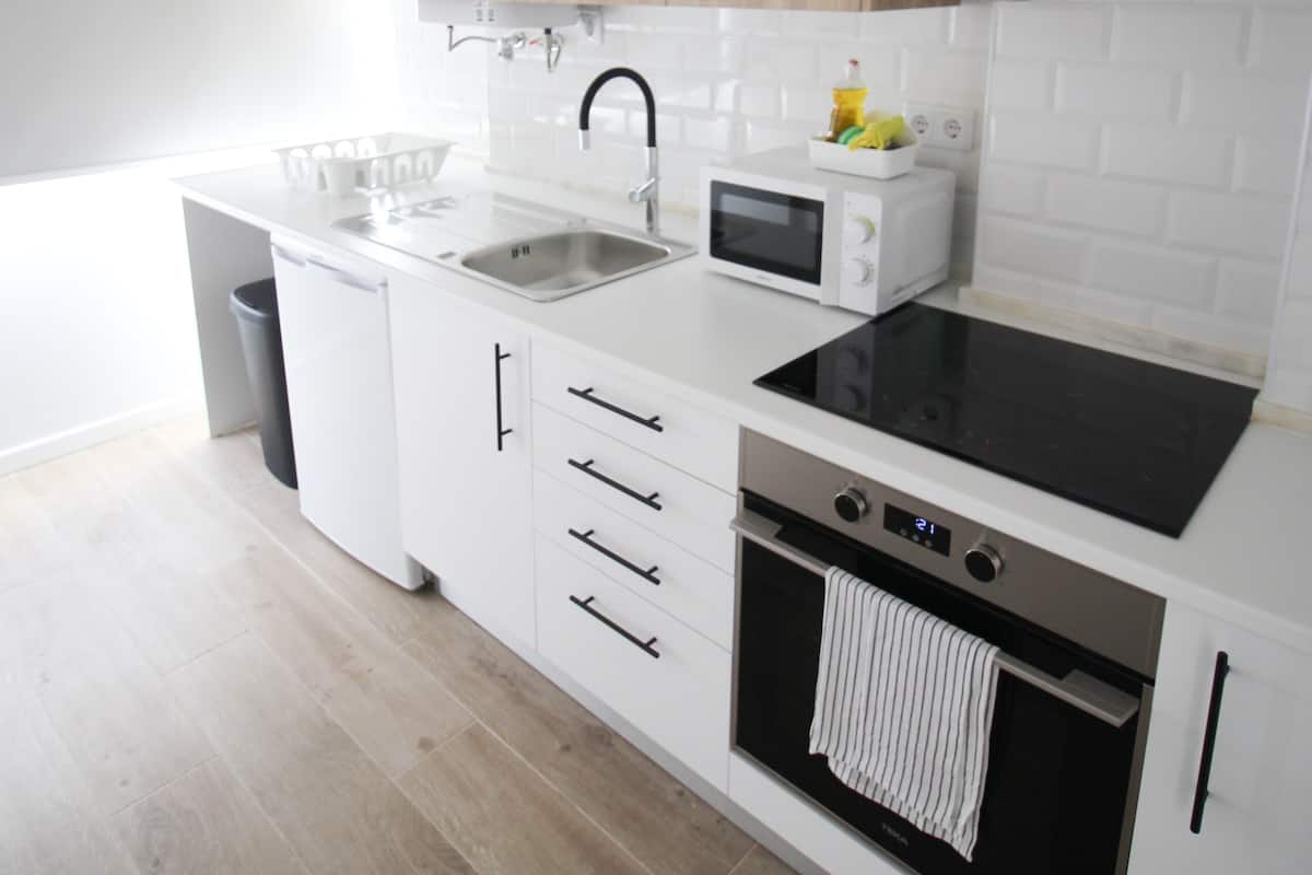 A modern kitchen with white cabinetry, a black stovetop, a microwave, and a built-in oven.