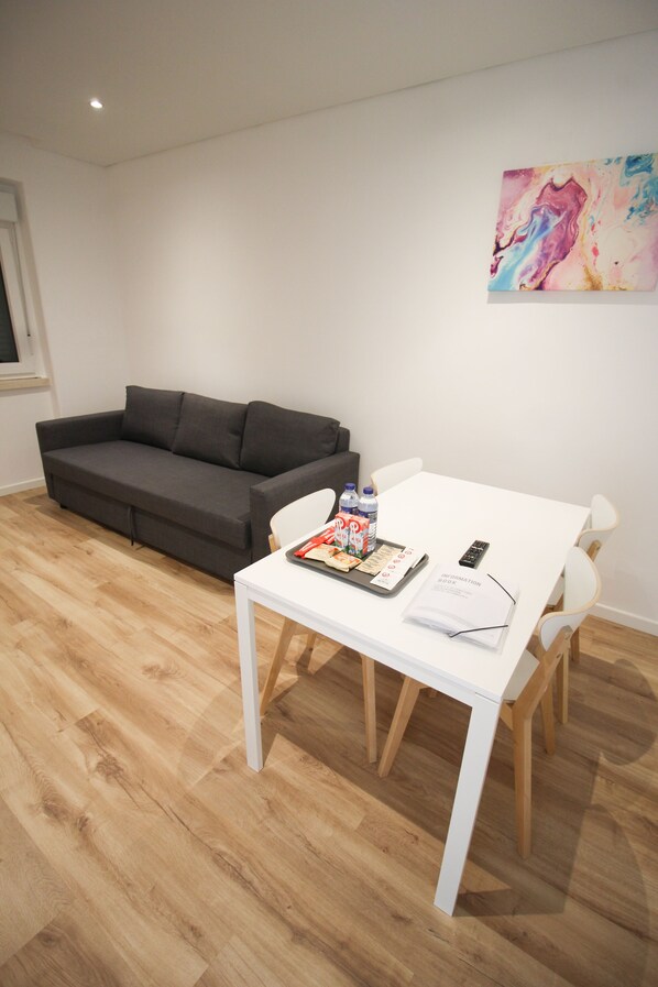 Una sala de estar moderna con un sofá gris, una mesa blanca y un cuadro en la pared.
