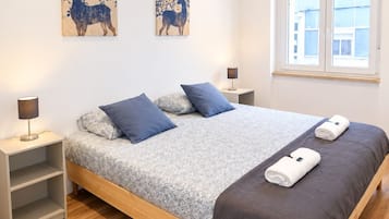 A modern bedroom with a wooden bed, two nightstands, a window, and two wall art pieces.