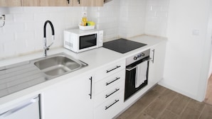A modern kitchen with white cabinetry, a microwave, a sink, and a built-in oven. - ORIENTE DNA STUDIOS X (Loures)