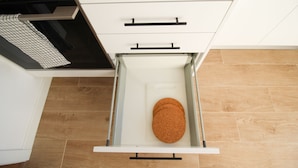 A kitchen with a white cabinet, a wooden floor, and a cork mat inside a drawer. - ORIENTE DNA STUDIOS X (Loures)