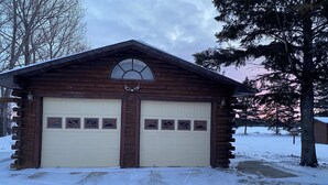 Un garage in legno con due grandi porte e un piccolo oblò sopra.