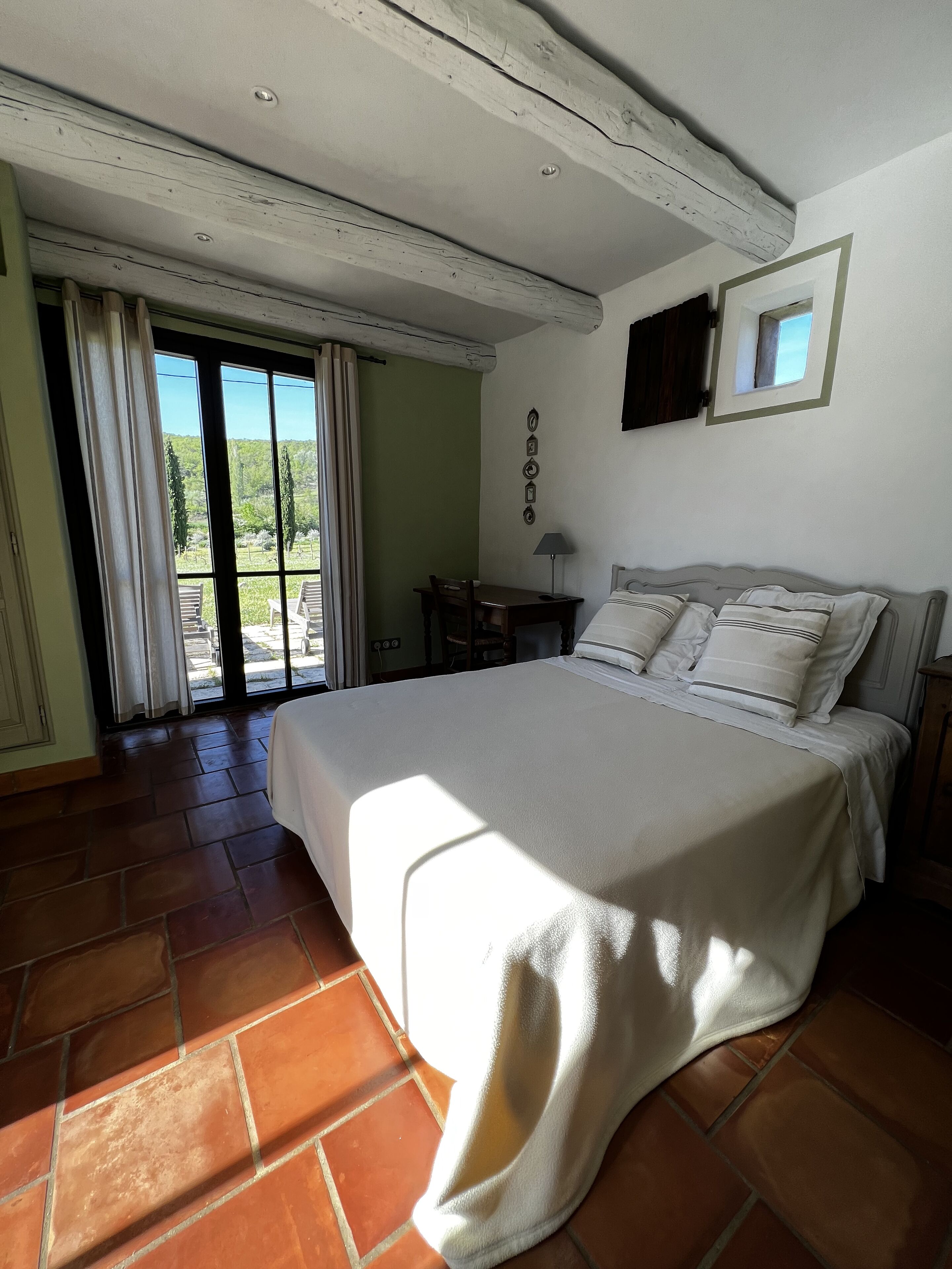Un dormitorio con una cama grande, un escritorio y vistas a través de un ventanal corredizo.