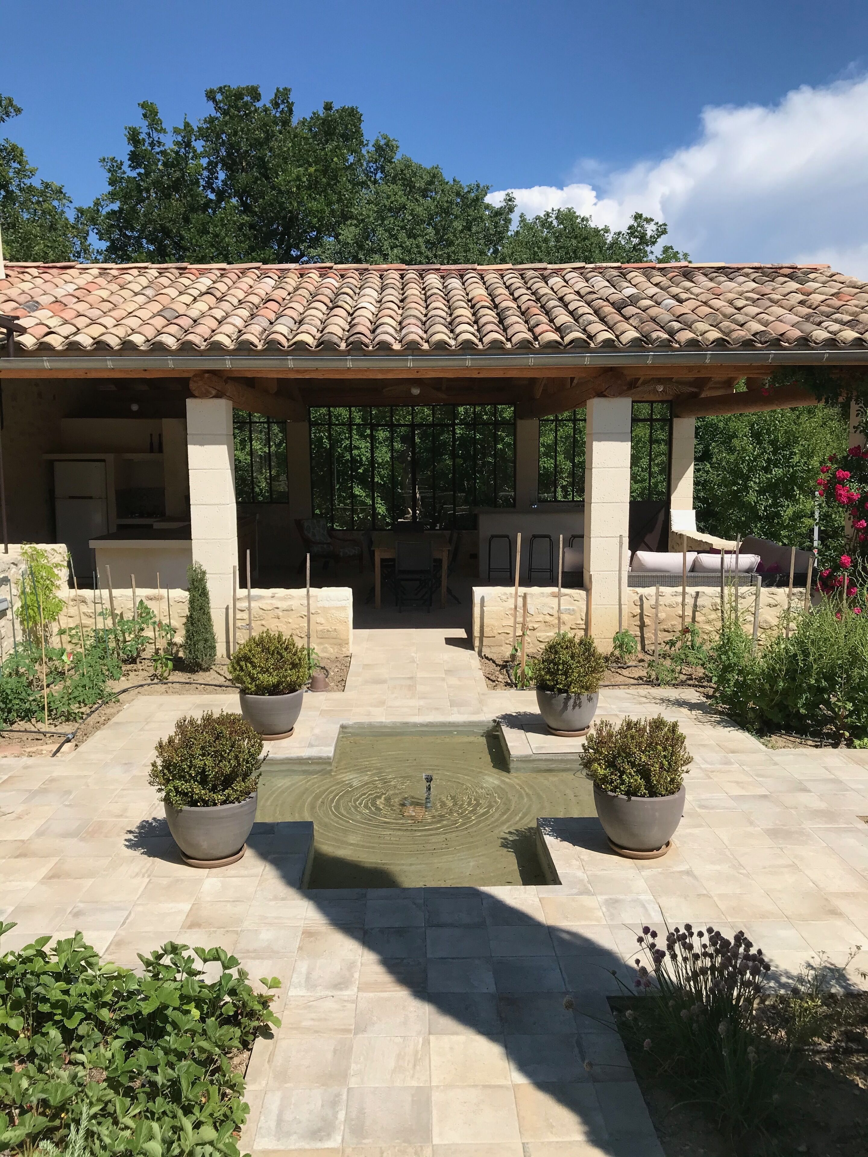 A covered patio area with a tiled roof, outdoor seating, and a central water feature.