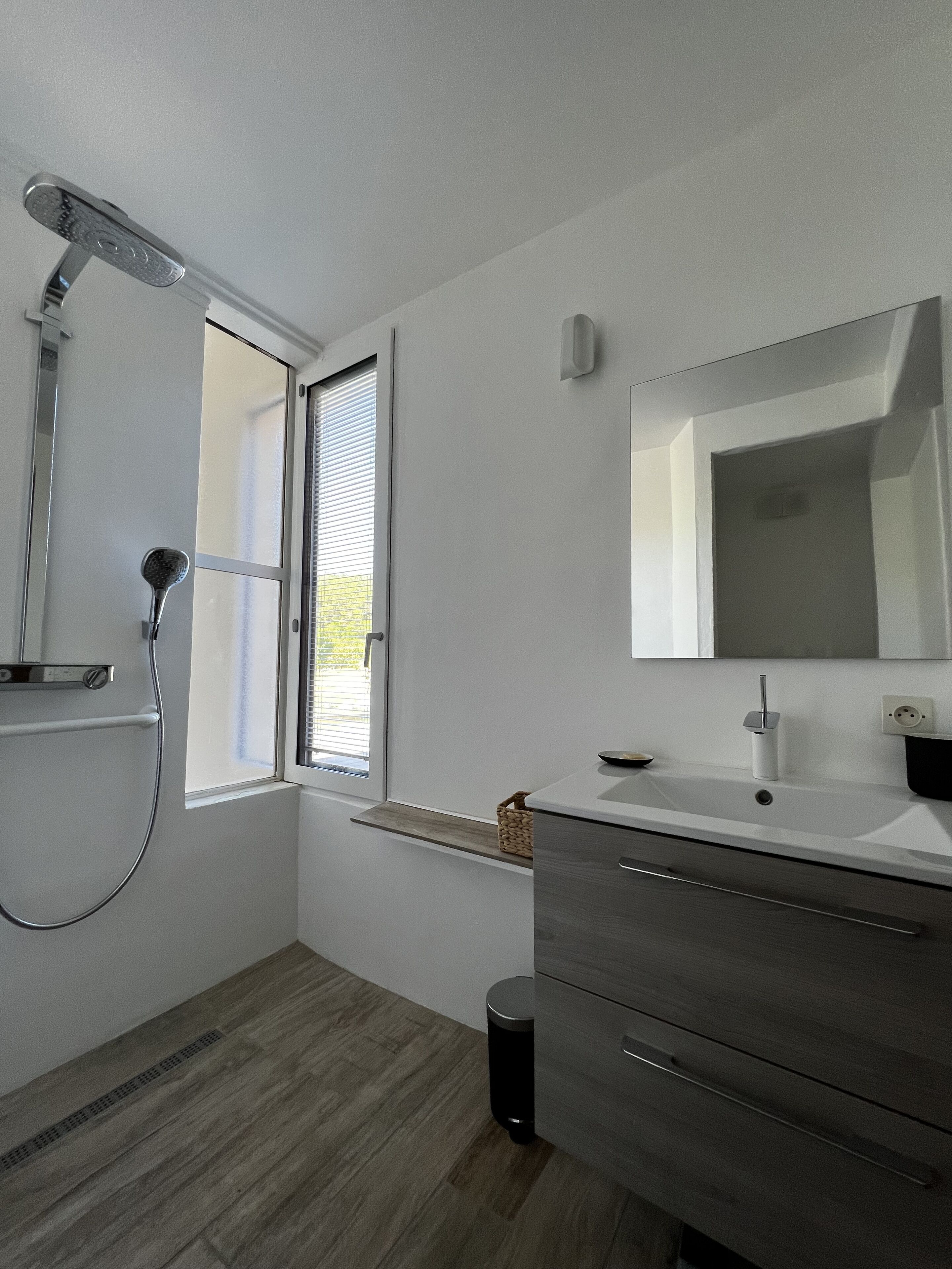 Un baño moderno con ducha, lavamanos y espejo.