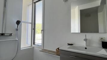 Un baño moderno con ducha, lavamanos y espejo.