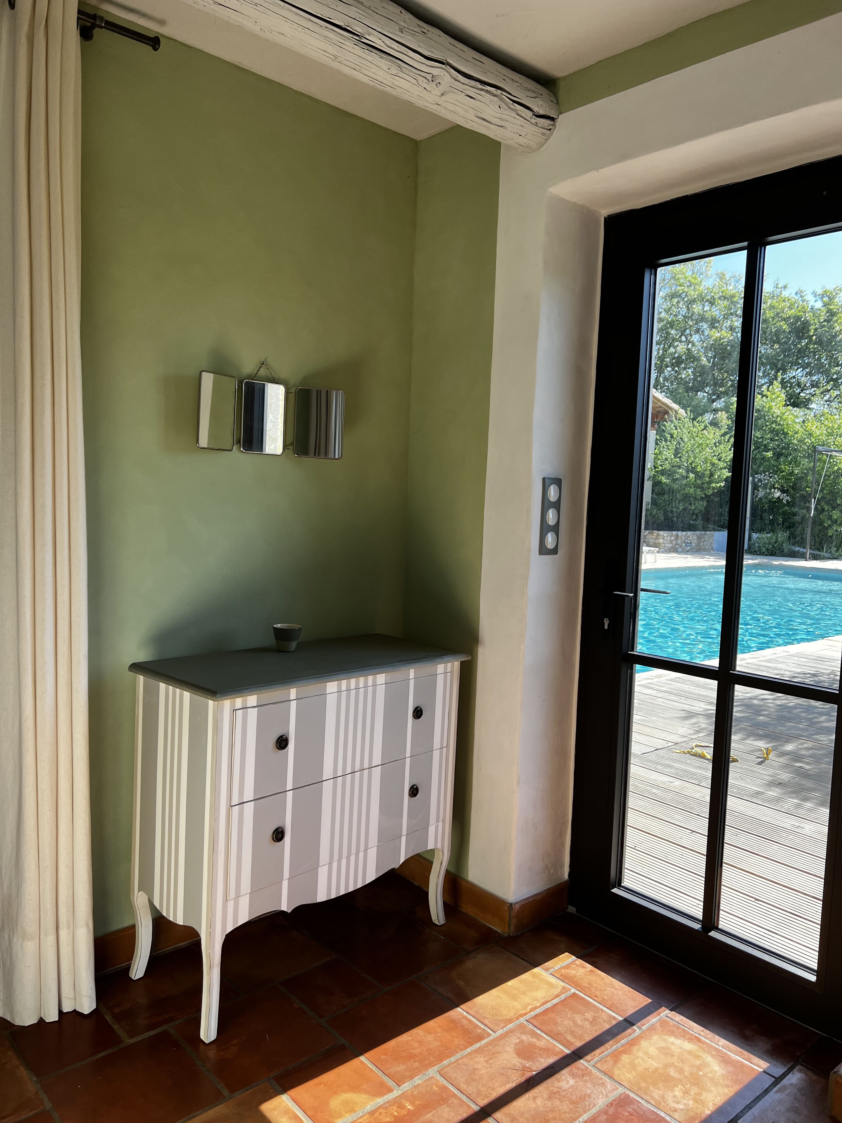 A room with a white cabinet, a sliding glass door leading to a pool, and a green wall.