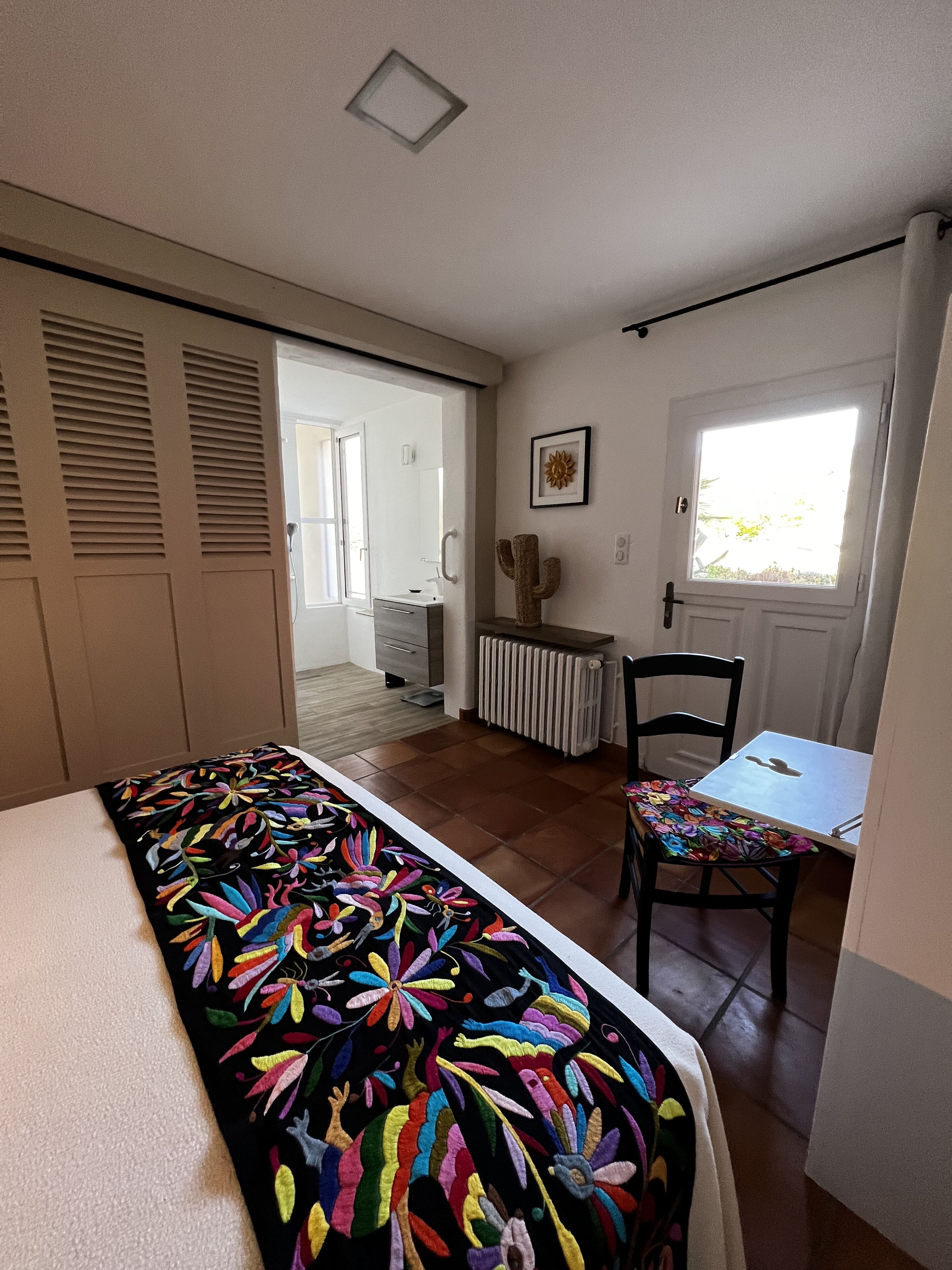 A bedroom with a bed, a chair, a table, and a window.