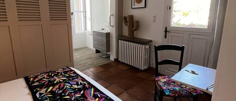 A bedroom with a bed, a chair, a table, and a window.