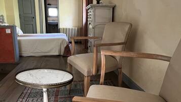 A room with a bed, a chair, a small table, a radiator, and a wardrobe.