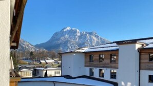 Un edifici modern amb teulada plana, grans finestres i vistes a muntanyes nevades.